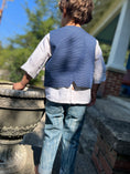 Load image into Gallery viewer, little boy with his back to the camera showing the detail in the blue textured chambray vest. He is wearing it with the button back off white linen shirt and textured skinny jeans