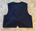 Load image into Gallery viewer, a flat lay view of the back of the blue textured chambray vest showing fabric detail and inverted "V" detail at the center bottom