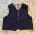 Load image into Gallery viewer, Flat lay view of the textured chambray vest showing the fabric detail and wood buttons