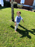 Load image into Gallery viewer, same little grinning boy with a farther away picture showing his light brown sandals and natural linen adventure pants worn with the double breasted waistcoat and white linen button down shirt