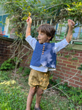 Load image into Gallery viewer, Little boy wearing the blue textured chambray vest, button back linen shirt and pleated cuffed shorts in khaki color twill