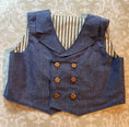 Load image into Gallery viewer, a flat view of the blue chambray double breasted waistcoat showing the collar detail and wood buttons down the front