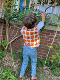 Load image into Gallery viewer, little boy with his back to the camera to show the back of the organic corduroy vest printed with large oranges