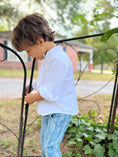 Load image into Gallery viewer, Little boy outside a gate wearing a white linen button down shirt with a poet color, natural wood buttons and monogram pocket