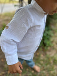 Load image into Gallery viewer, Side view of the sleeve of the white linen button down shirt