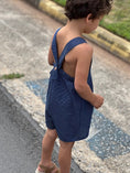 Load image into Gallery viewer, Side view of the romper showing the loose fit and strap detail