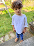 Load image into Gallery viewer, little boy in off white linen shirt with long sleeves rolled up to below the elbows and wearing blue chambray pants