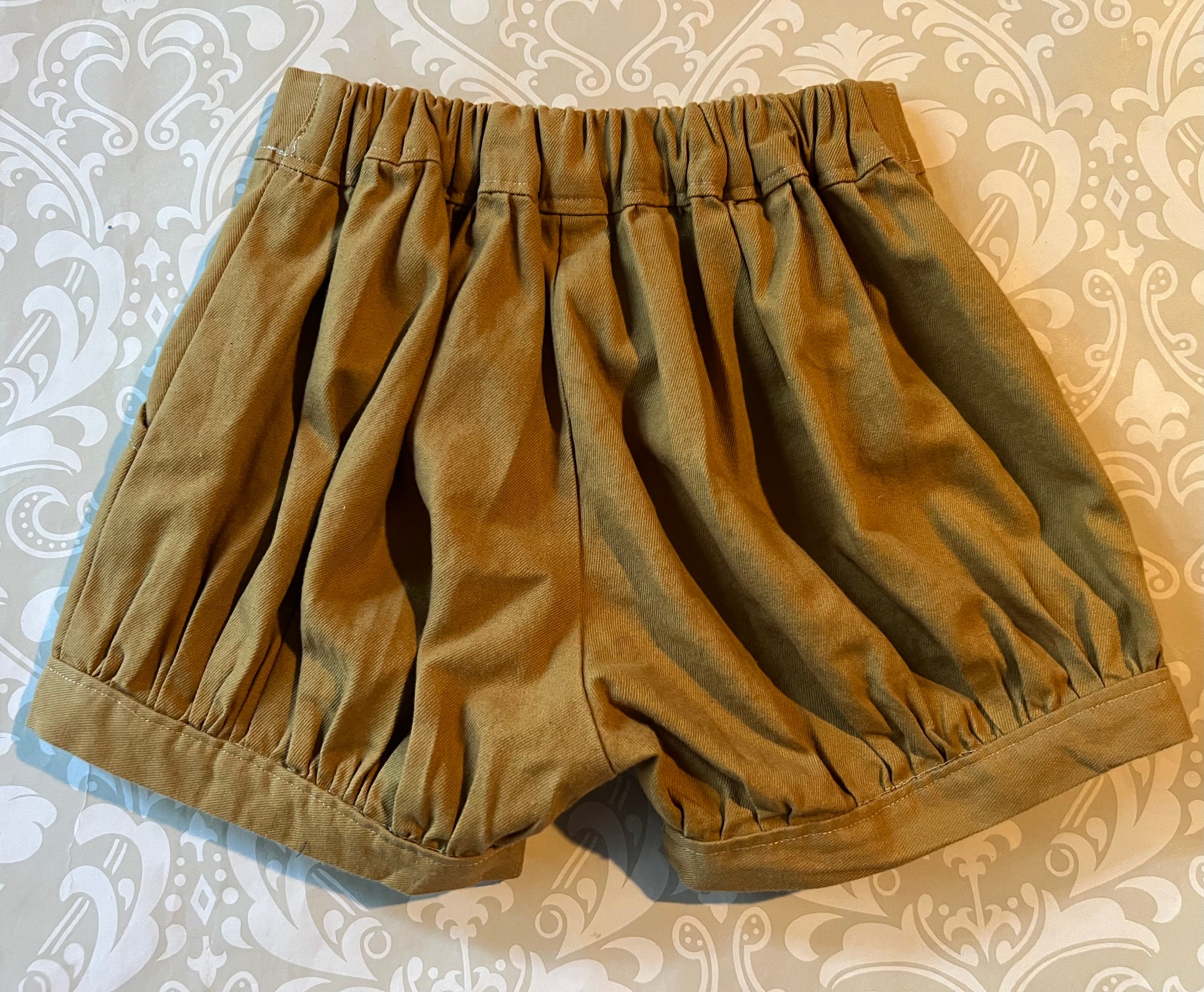 Flat lay view of the pleated cuffed shorts showing the elastic waist at the back 
