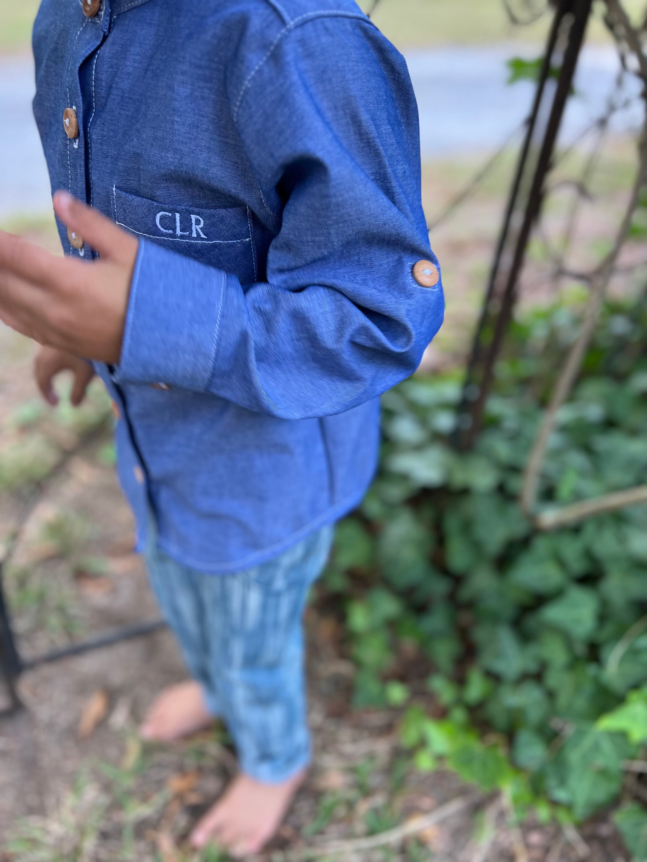closeup of the sleeve of the blue chambray button down shirt showing the wood button on the outside for the sleeve tab