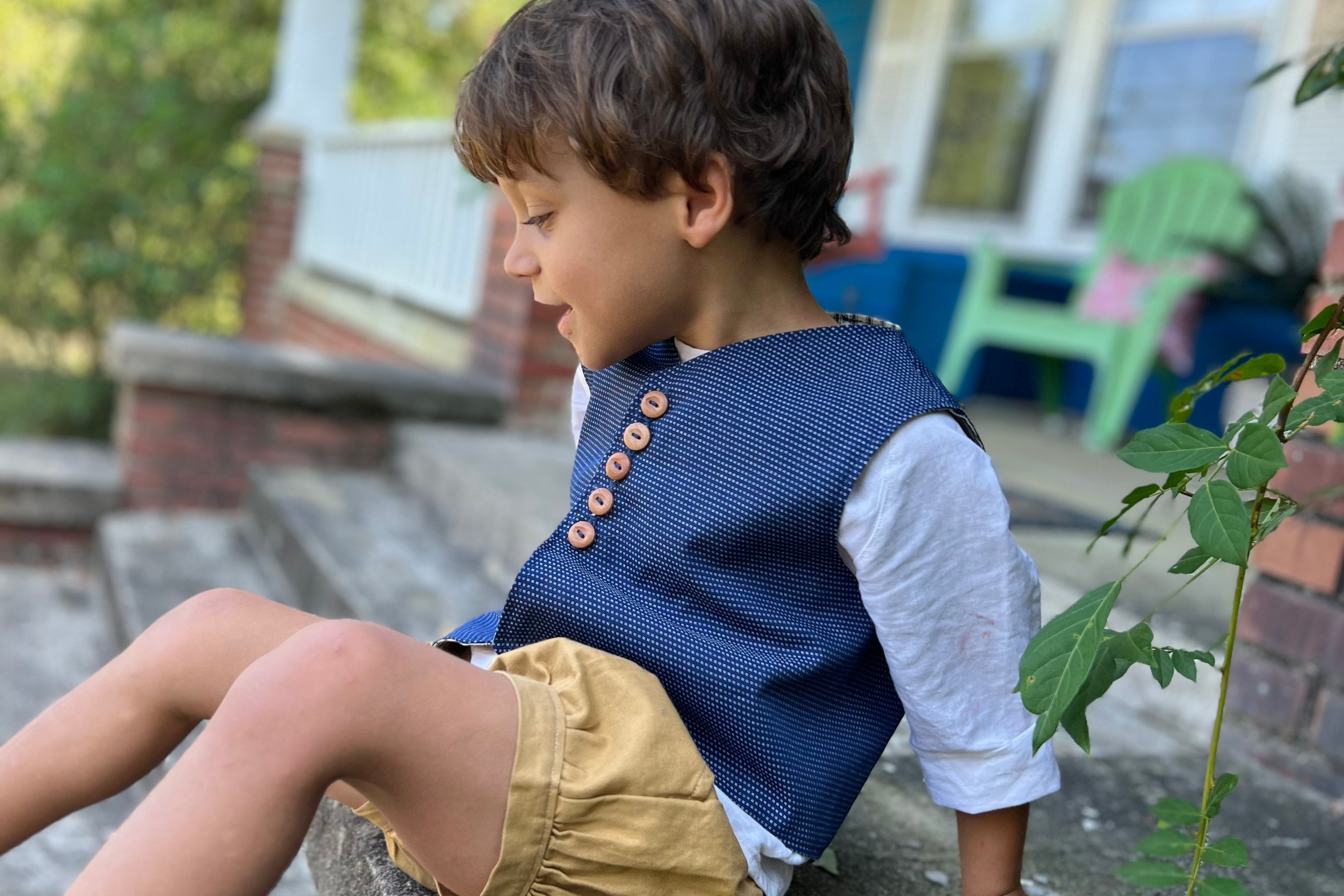 little boy wearing our textured chambray vest, linen button back shirt and pleated cuffed shorts in khaki