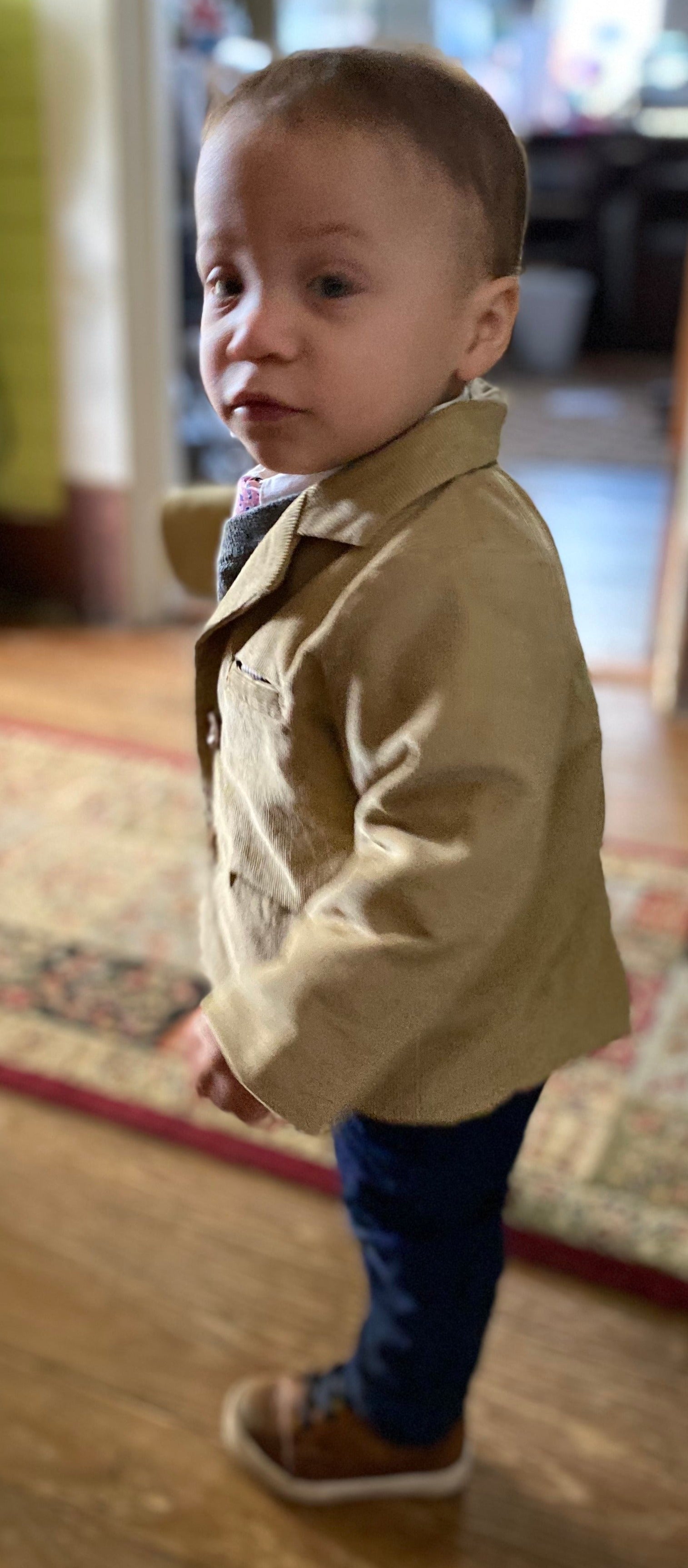 Toddler in profile wearing a tan corduroy sportscoat and jeans
