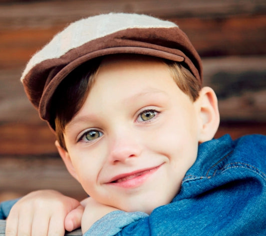 boy wearing a brown and cream newsboy cap
