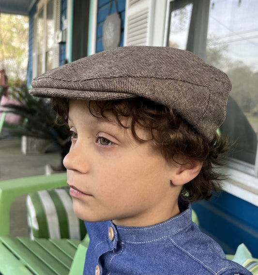 young boy wearing a light brown tweed newsboy cap in a side view