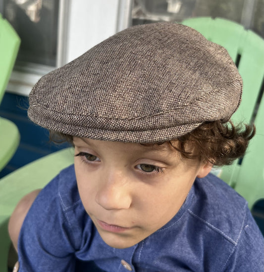 front and top view of a young boy wearing a light brown tweed newsboy cap