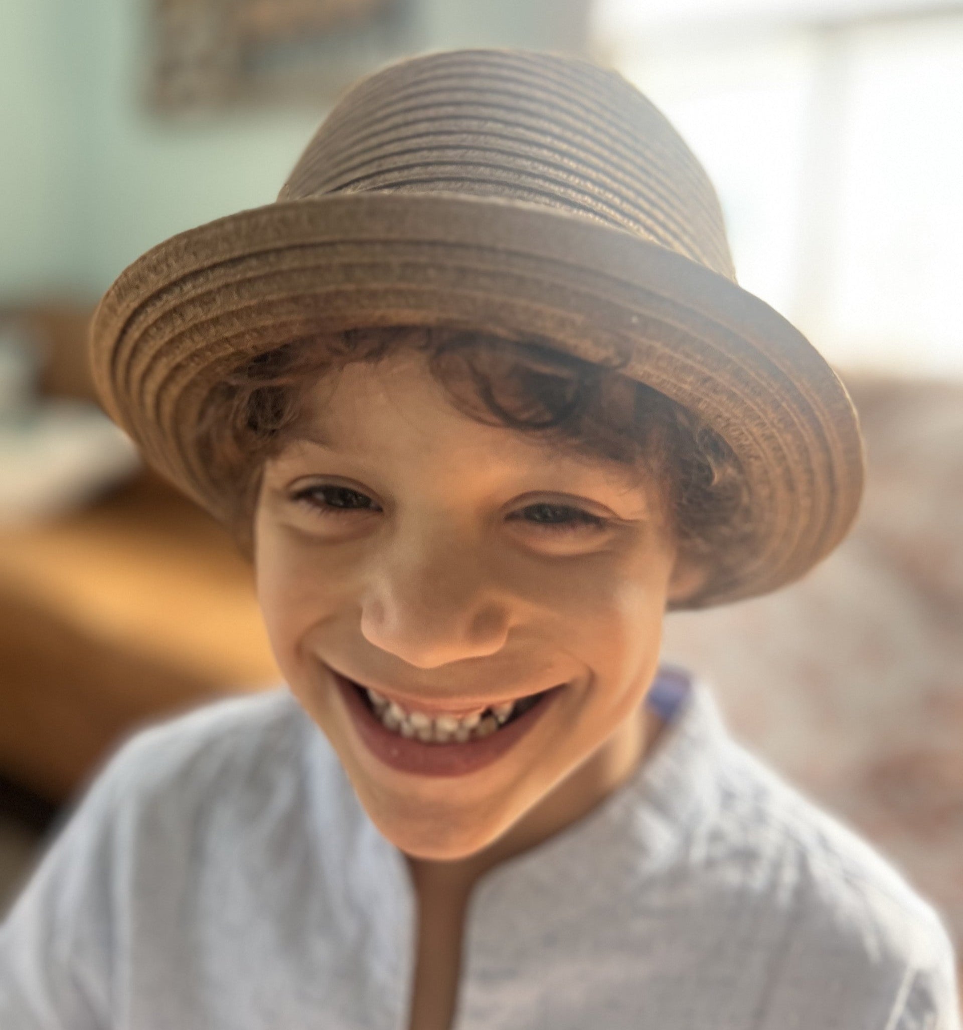 smiling boy wearing a dark brown straw fedora