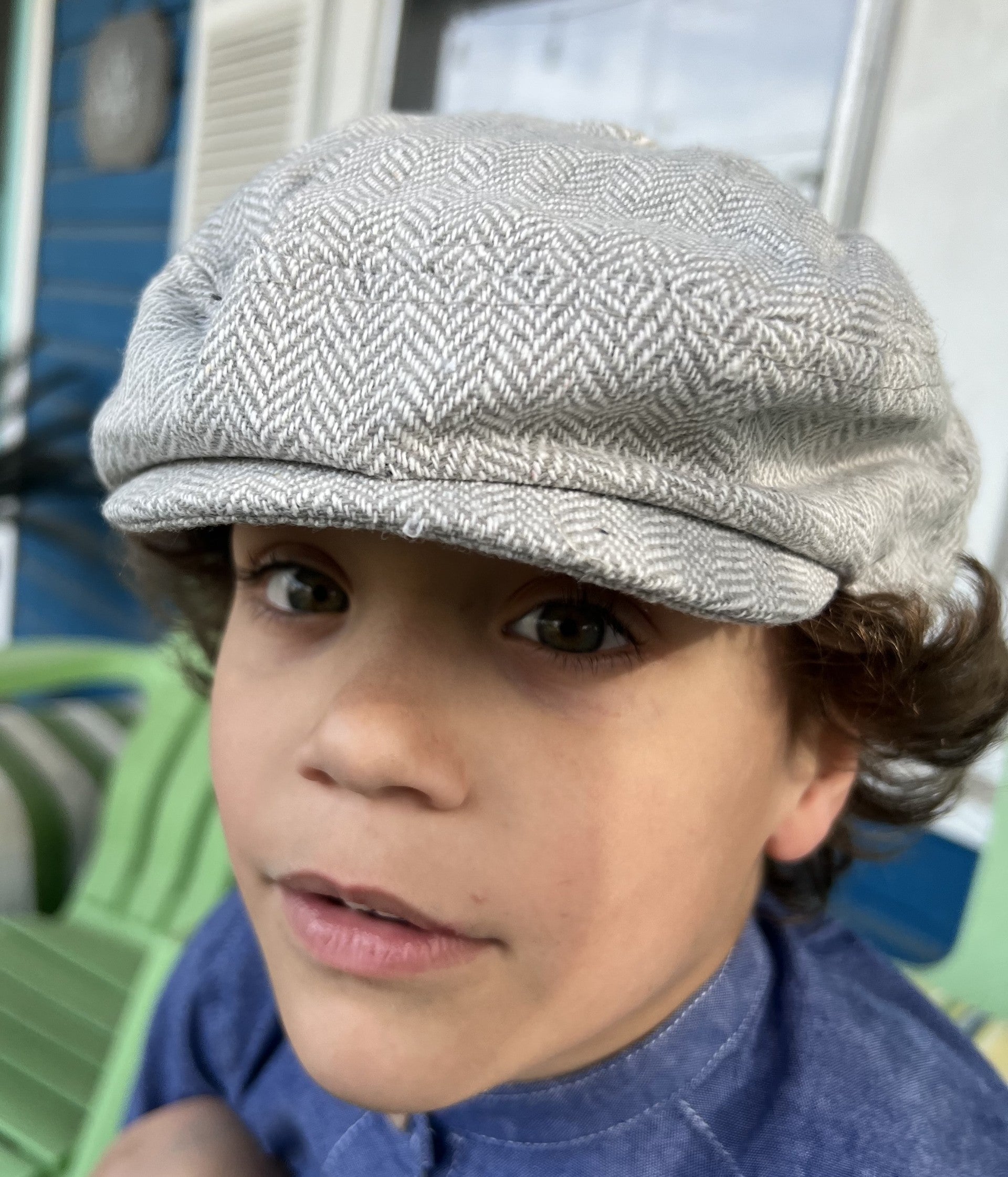 boy wearing  a gray herringbone tweed newsboy cap in a front view