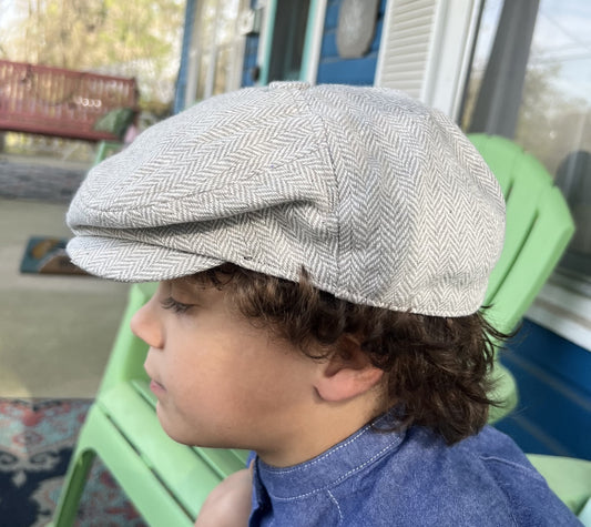 boy wearing  a gray herringbone tweed newsboy cap in a side view